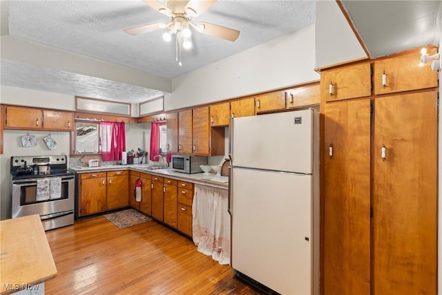 kitchen featuring stainless steel appliances, sink, light hardwood / wood-style flooring, and a textured ceiling