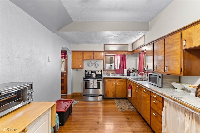 kitchen featuring sink, light hardwood / wood-style flooring, stainless steel appliances, and a textured ceiling