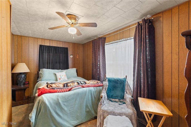 bedroom with ceiling fan and wooden walls