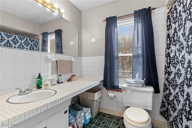 bathroom featuring vanity, a wealth of natural light, tile walls, and toilet