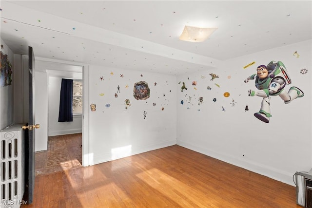 empty room featuring hardwood / wood-style flooring and radiator heating unit