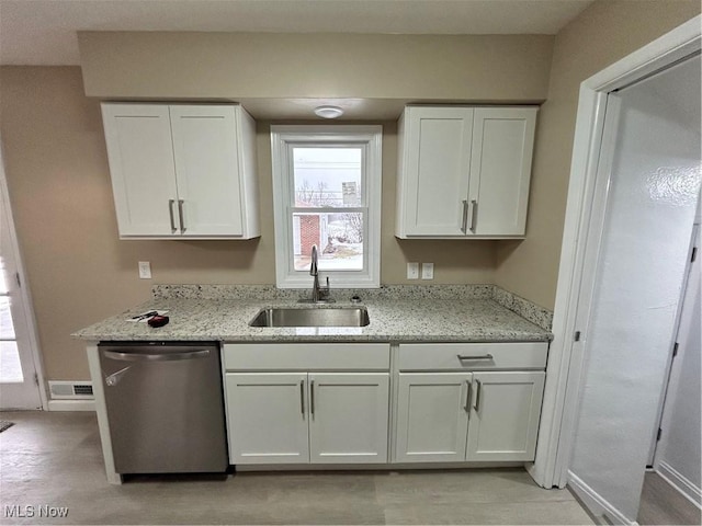 kitchen featuring dishwasher, sink, light stone countertops, and white cabinets