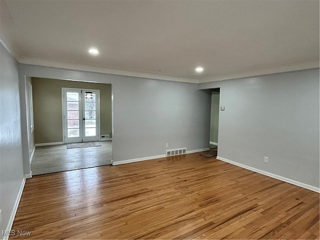 unfurnished room featuring crown molding, light hardwood / wood-style flooring, and french doors