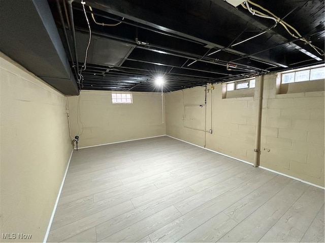 basement with plenty of natural light and light hardwood / wood-style flooring