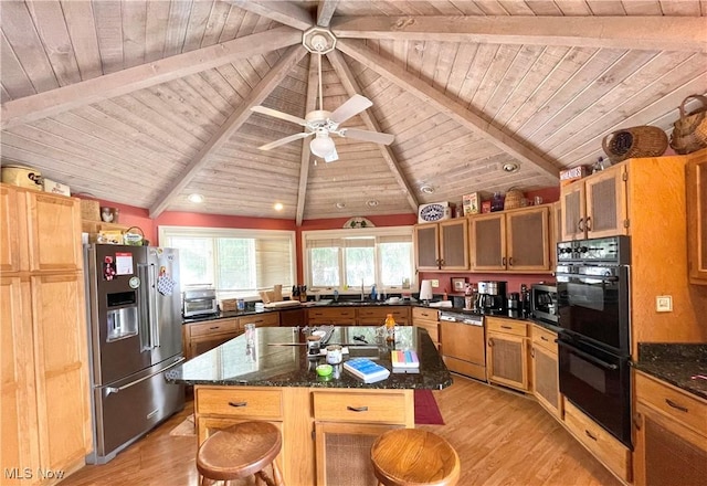 kitchen featuring a kitchen island, a breakfast bar area, dark stone counters, stainless steel appliances, and light wood-type flooring