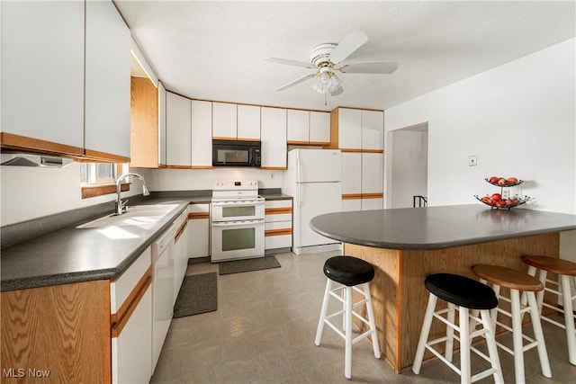 kitchen with sink, white appliances, white cabinets, and a kitchen bar