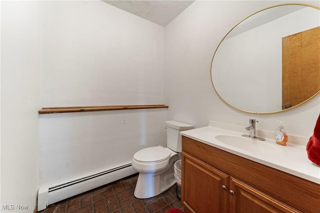 bathroom featuring vanity, a textured ceiling, toilet, and baseboard heating