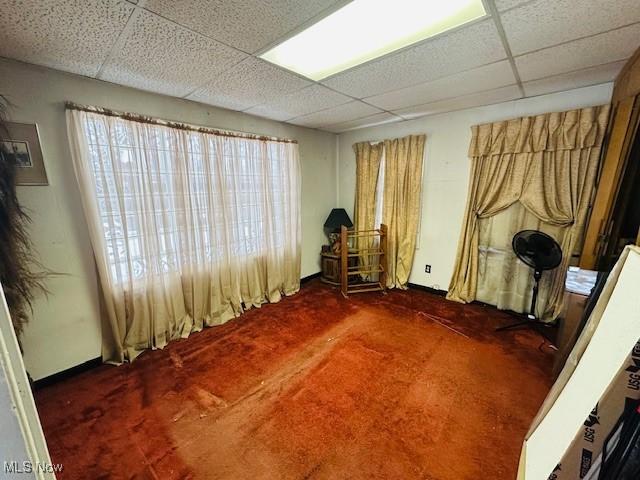 interior space featuring dark colored carpet and a paneled ceiling