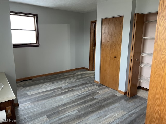 unfurnished bedroom featuring hardwood / wood-style flooring and multiple closets