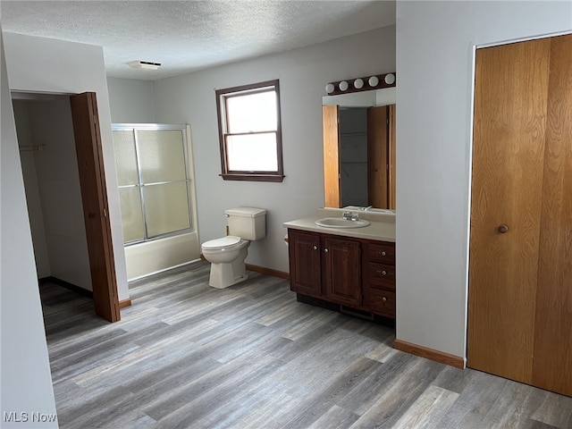 full bathroom with hardwood / wood-style floors, enclosed tub / shower combo, toilet, and a textured ceiling