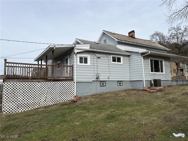 view of property exterior featuring central AC unit, a deck, and a lawn