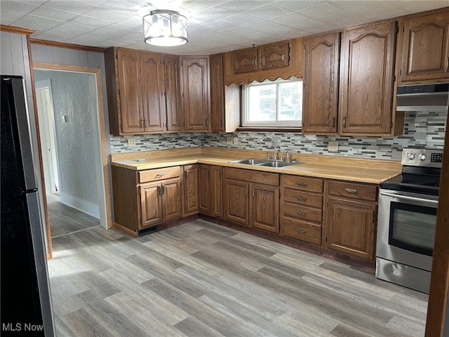 kitchen with stainless steel appliances, sink, backsplash, and light hardwood / wood-style flooring