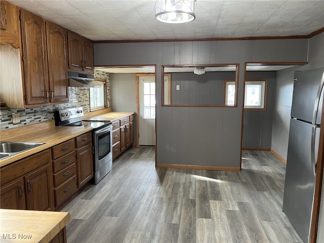 kitchen featuring tasteful backsplash, extractor fan, appliances with stainless steel finishes, and light hardwood / wood-style flooring