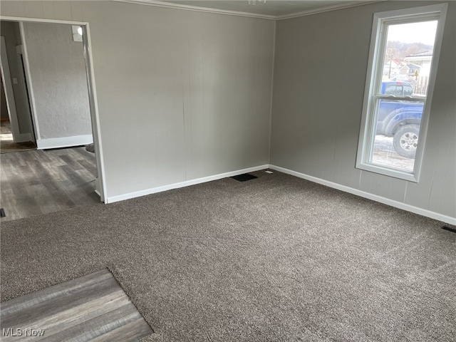 empty room with ornamental molding and dark colored carpet