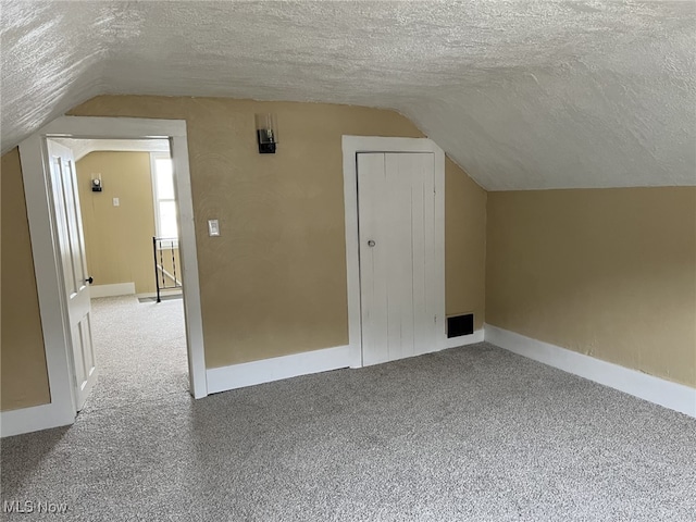 bonus room featuring lofted ceiling, carpet flooring, and a textured ceiling