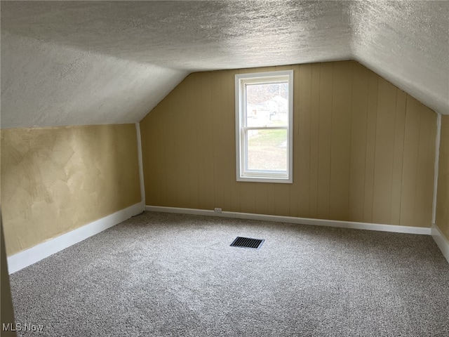 bonus room featuring lofted ceiling, carpet floors, and a textured ceiling