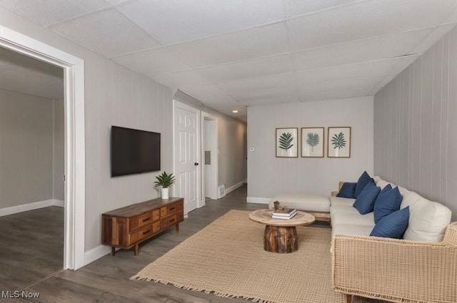 living room featuring dark hardwood / wood-style flooring and a paneled ceiling