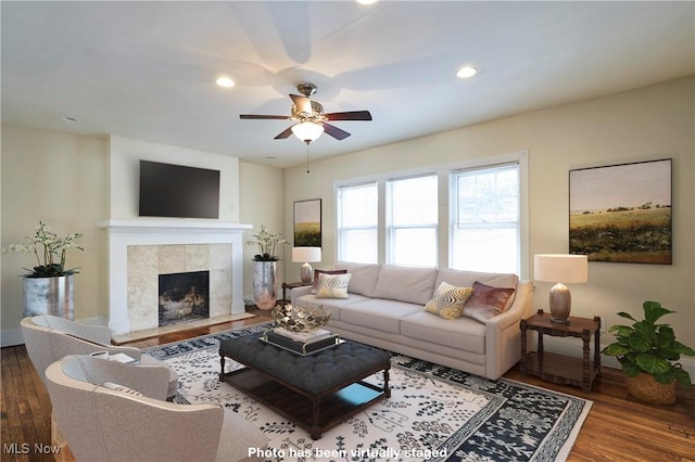 living room featuring wood-type flooring, ceiling fan, and a fireplace