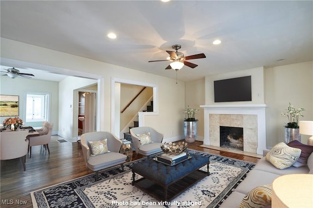 living room featuring ceiling fan, wood-type flooring, and a tiled fireplace