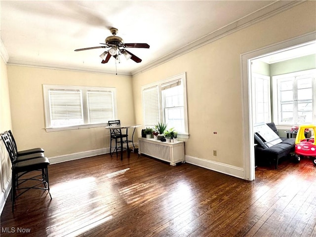 living area with dark wood-type flooring, radiator heating unit, ornamental molding, and plenty of natural light