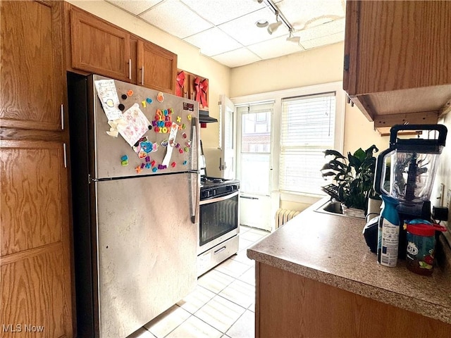 kitchen with rail lighting, sink, light tile patterned floors, stainless steel appliances, and a drop ceiling