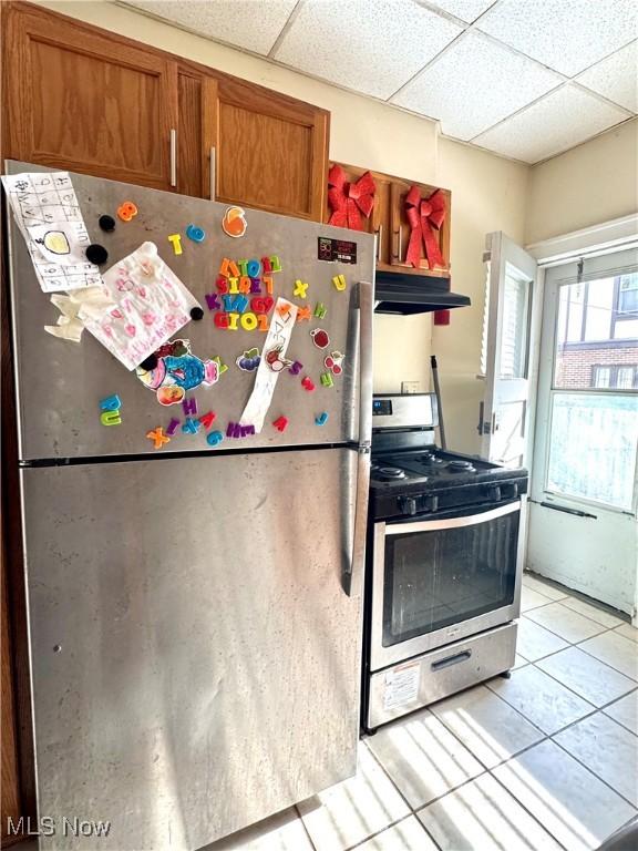 kitchen featuring a drop ceiling, light tile patterned floors, and stainless steel appliances