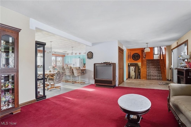 carpeted living room with an inviting chandelier