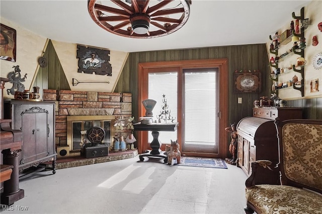 sitting room featuring plenty of natural light, a stone fireplace, and wood walls