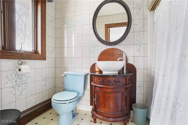 bathroom featuring tile walls, sink, toilet, and walk in shower