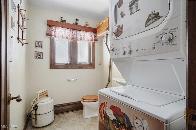 bathroom featuring stacked washer / dryer, vanity, tile patterned floors, and toilet