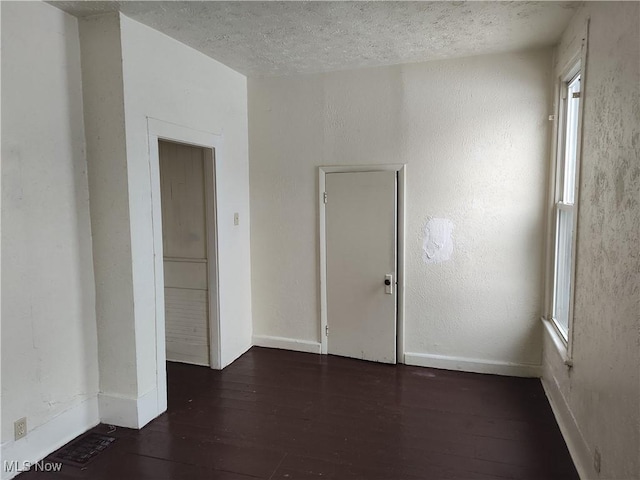 empty room with dark wood-type flooring and a textured ceiling