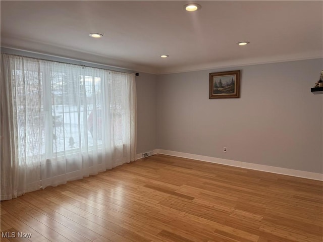 empty room featuring crown molding and light wood-type flooring