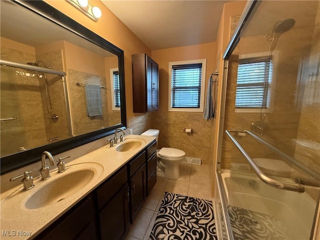 bathroom featuring tile patterned floors, toilet, an enclosed shower, tile walls, and vanity