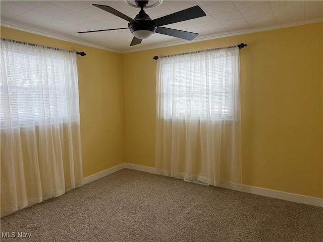 carpeted spare room featuring crown molding, ceiling fan, and a wealth of natural light