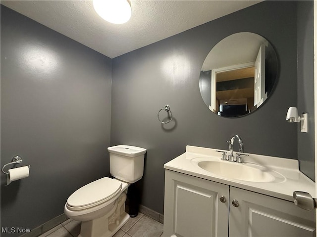 bathroom with tile patterned flooring, vanity, a textured ceiling, and toilet