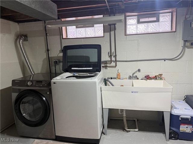 washroom featuring water heater, sink, and washing machine and clothes dryer