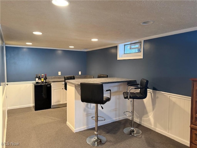 bar with white cabinetry, ornamental molding, carpet floors, and a textured ceiling