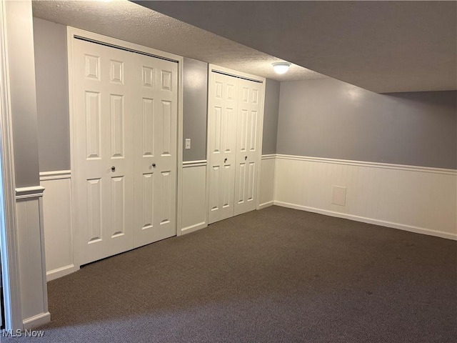 basement featuring a textured ceiling and dark colored carpet