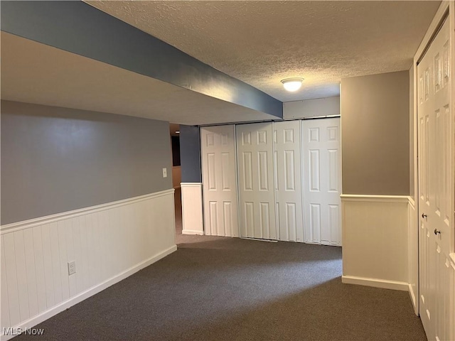 basement with dark carpet and a textured ceiling