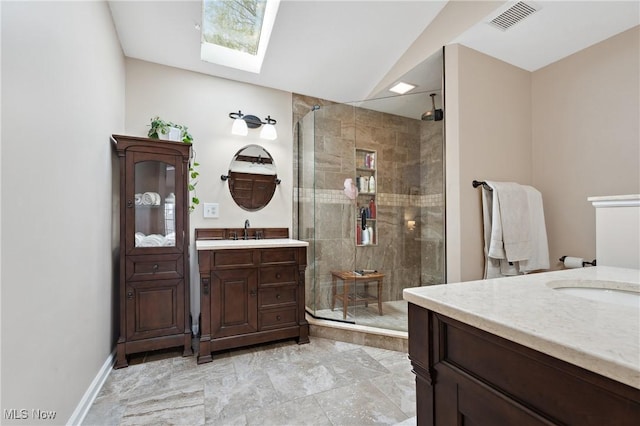 bathroom with vanity, a skylight, and a shower with door