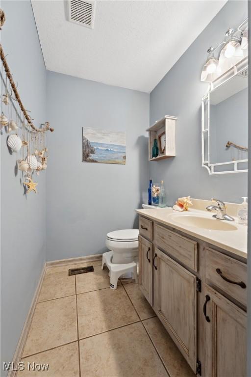 bathroom featuring tile patterned flooring, vanity, and toilet