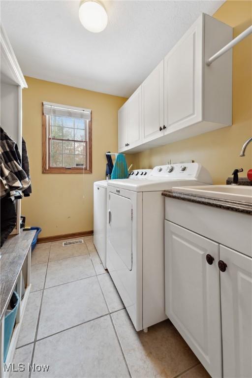 laundry room with independent washer and dryer, cabinets, sink, and light tile patterned floors