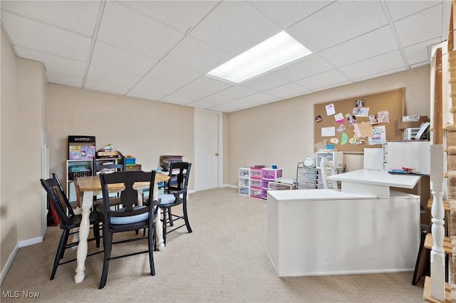 dining space featuring light carpet and a paneled ceiling