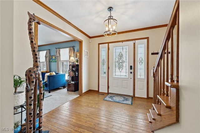 entrance foyer featuring hardwood / wood-style flooring, ornamental molding, and a chandelier