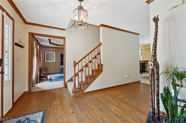 foyer entrance featuring ornamental molding, an inviting chandelier, and light hardwood / wood-style flooring