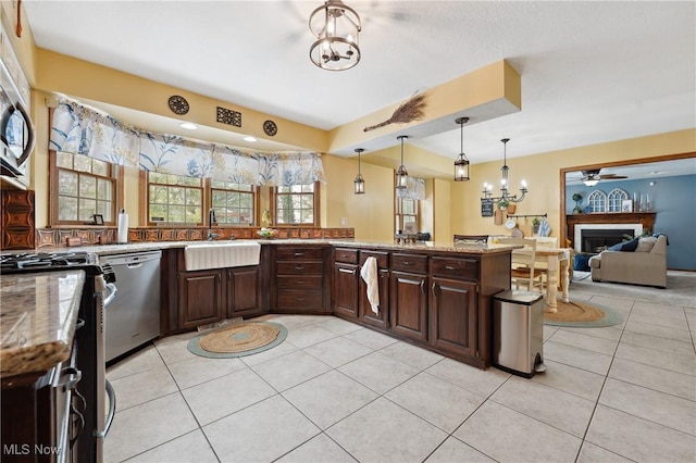 kitchen featuring light tile patterned flooring, dark brown cabinetry, sink, hanging light fixtures, and dishwasher