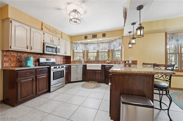 kitchen with sink, a kitchen bar, decorative backsplash, dark brown cabinetry, and stainless steel appliances