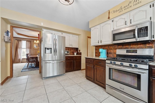 kitchen with white cabinetry, stainless steel appliances, decorative backsplash, and light tile patterned floors