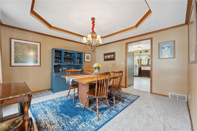 dining room with light carpet, a notable chandelier, ornamental molding, and a raised ceiling