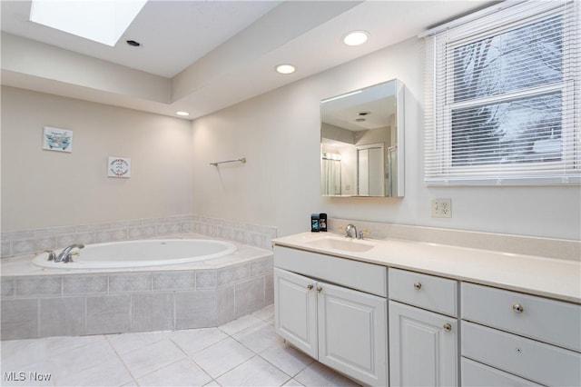 bathroom with vanity, a skylight, tile patterned floors, and tiled bath